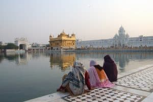 Fyra personer sitter vid en sjö och tittar på ett tempel i Indien.