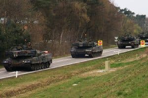 Leopard 2-stridsvagnar som kör i kolonn på en allmän väg under övning.