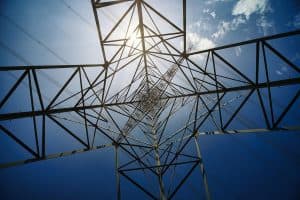 A high-voltage power line tower against a blue sky.