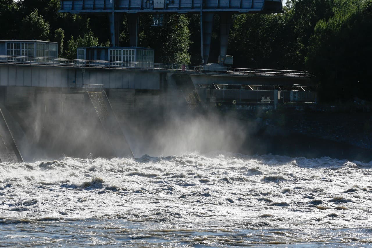 A dam with water flowing vigorously, illustrating hydroelectric power generation.