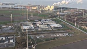 Flygbild över ett Google-datacenter omgivet av vindkraftverk och industrianläggningar.