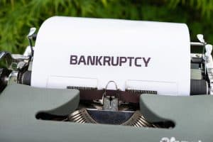 Närbild av en skrivmaskin med papper där det står 'BANKRUPTCY'.
