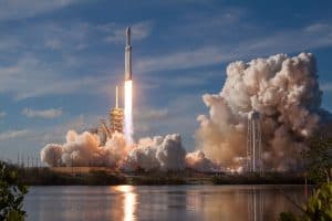En SpaceX Falcon Heavy-raket som skjuts upp mot himlen med rök som bolmar omkring.
