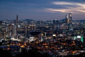 Vy över Seoul med skyskrapor och stadsljus i skymningen.