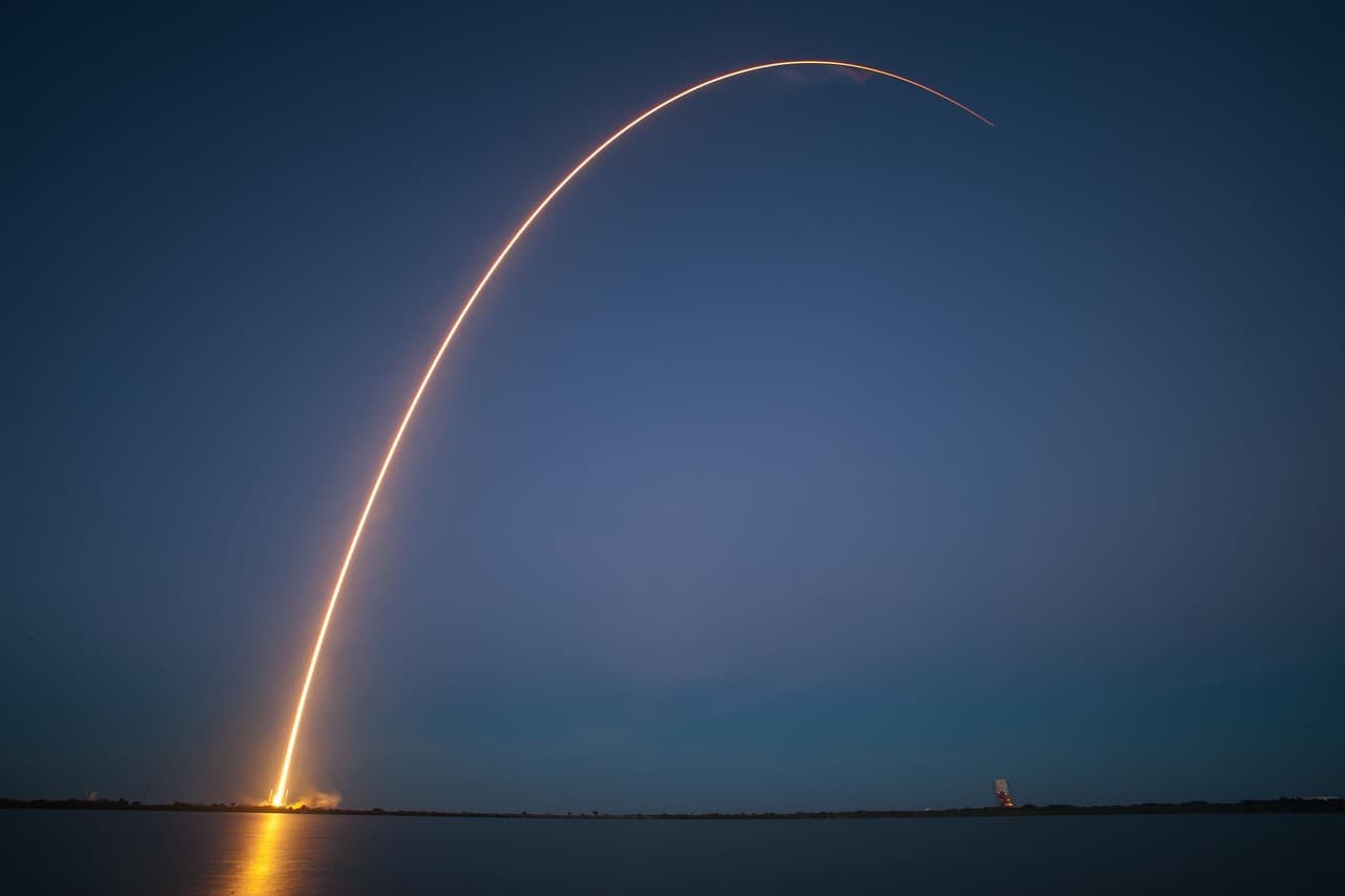 En raketuppskjutning med en ljusbåge mot natthimlen.