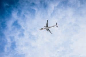 Ett flygplan flyger högt upp i himlen med moln i bakgrunden.
