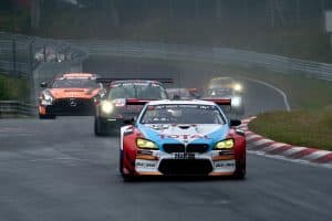 En BMW-bil tävlar på en racerbana med andra bilar i bakgrunden.