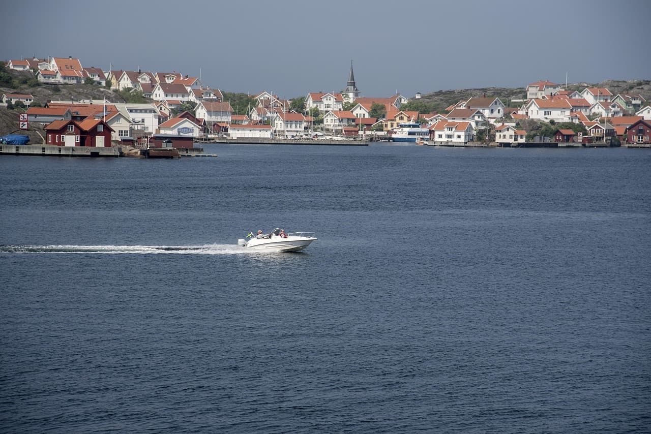 Motorbåt på havet framför en kuststad i Bohuslän.