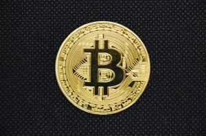 Guldmynt med Bitcoin-symbol på svart bakgrund.