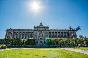 Sveriges riksdag med svenska och EU-flaggor i förgrunden.