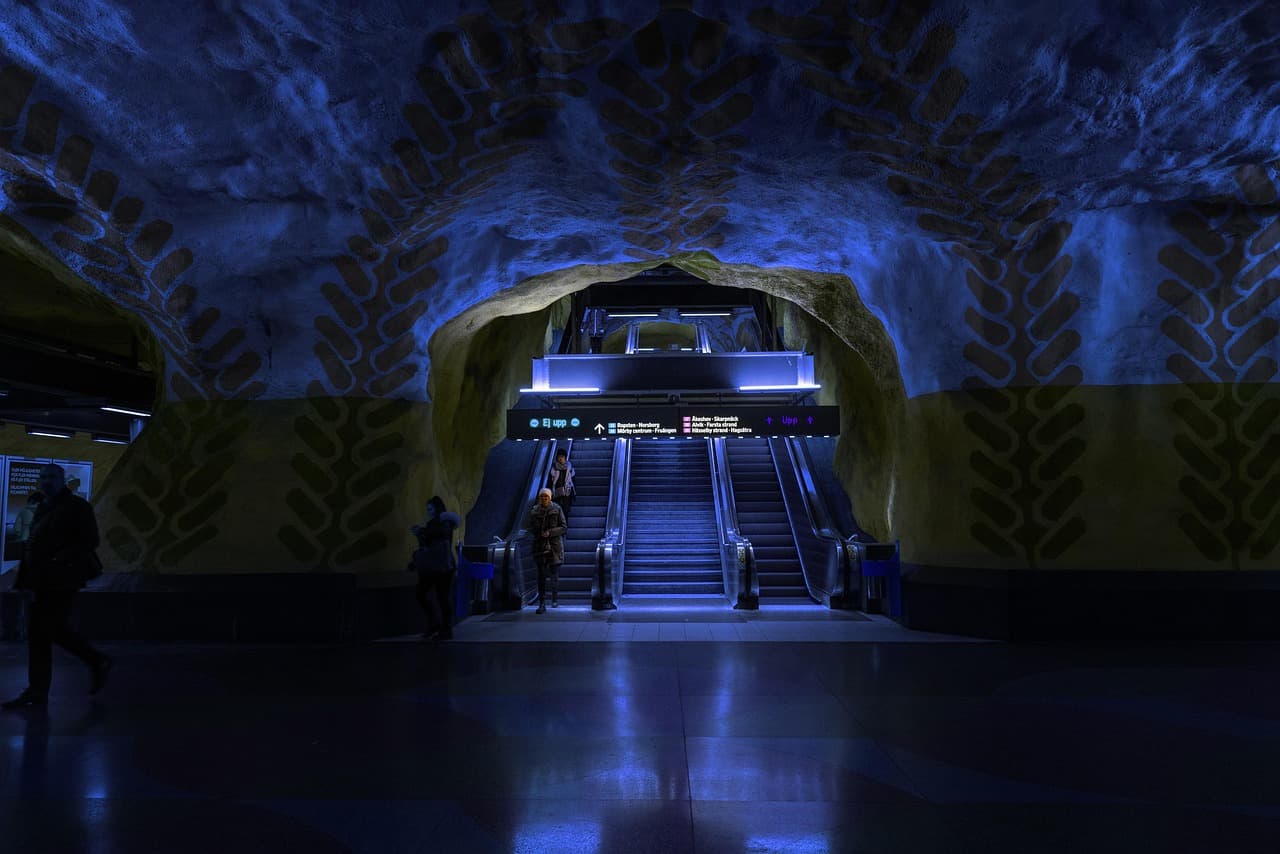 En tunnelbanestation med blå belysning och rulltrappor.