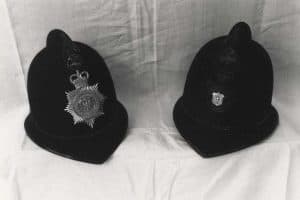 Två polishjälmar från East Riding Constabulary på ett bord.