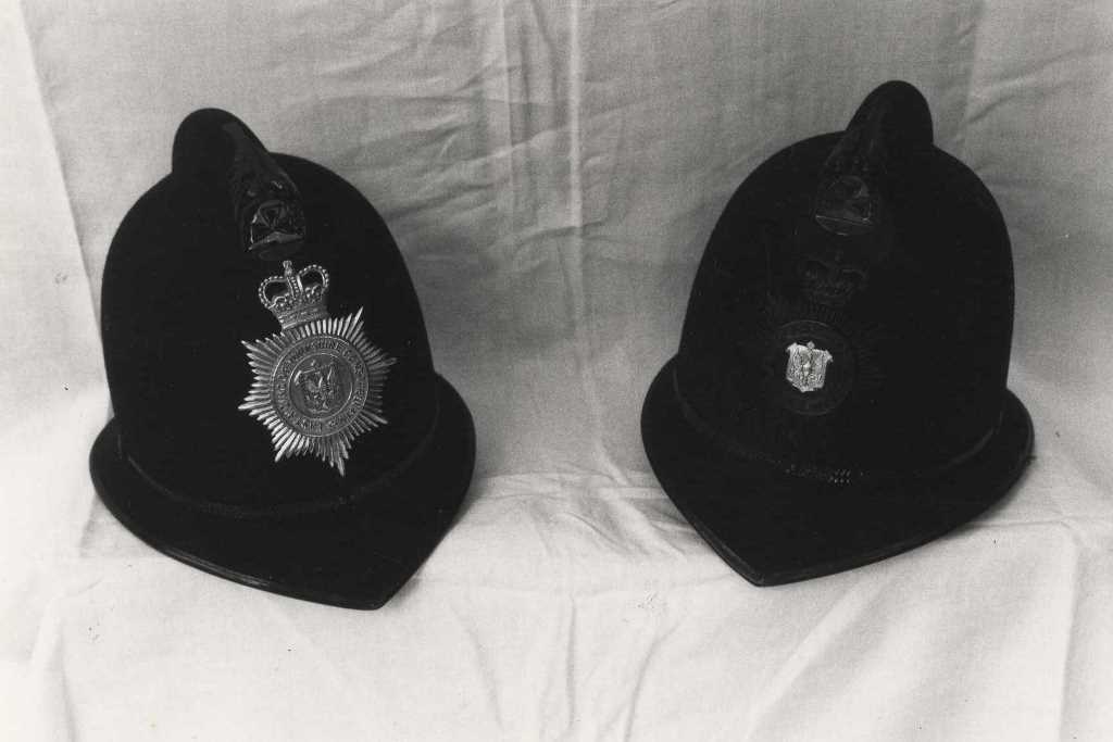 Två polishjälmar från East Riding Constabulary på ett bord.