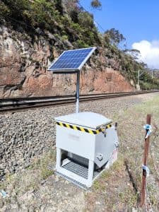 Solar powered railway track lubricator near railway tracks.