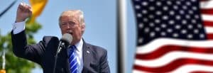 Donald Trump talar vid ett evenemang med en amerikansk flagga i bakgrunden.