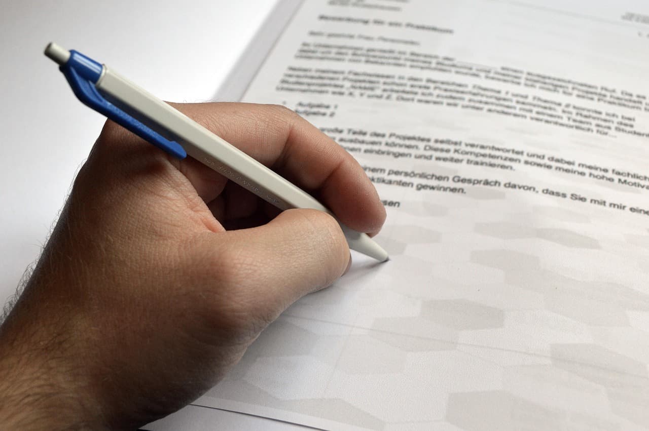 Hand holding a pen writing on a document.