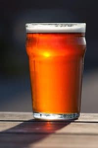 Ett glas öl på ett bord i solljus.