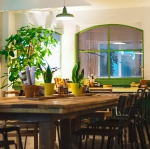Interiör av en restaurang med träbord och gröna växter.