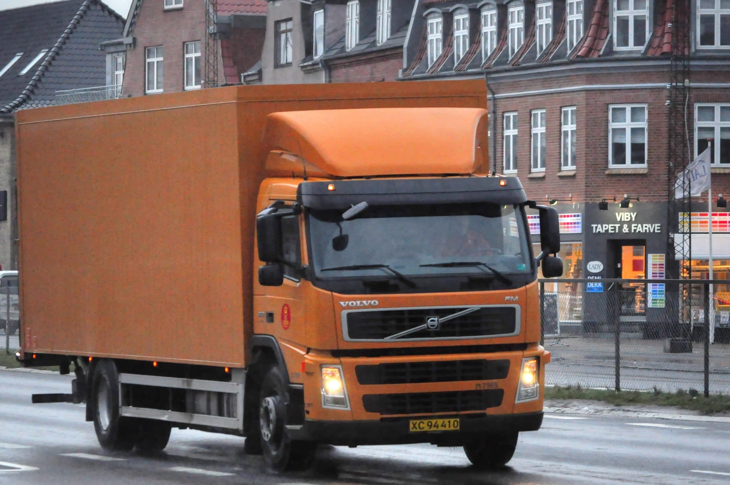 Orange Volvo truck driving on a city street.