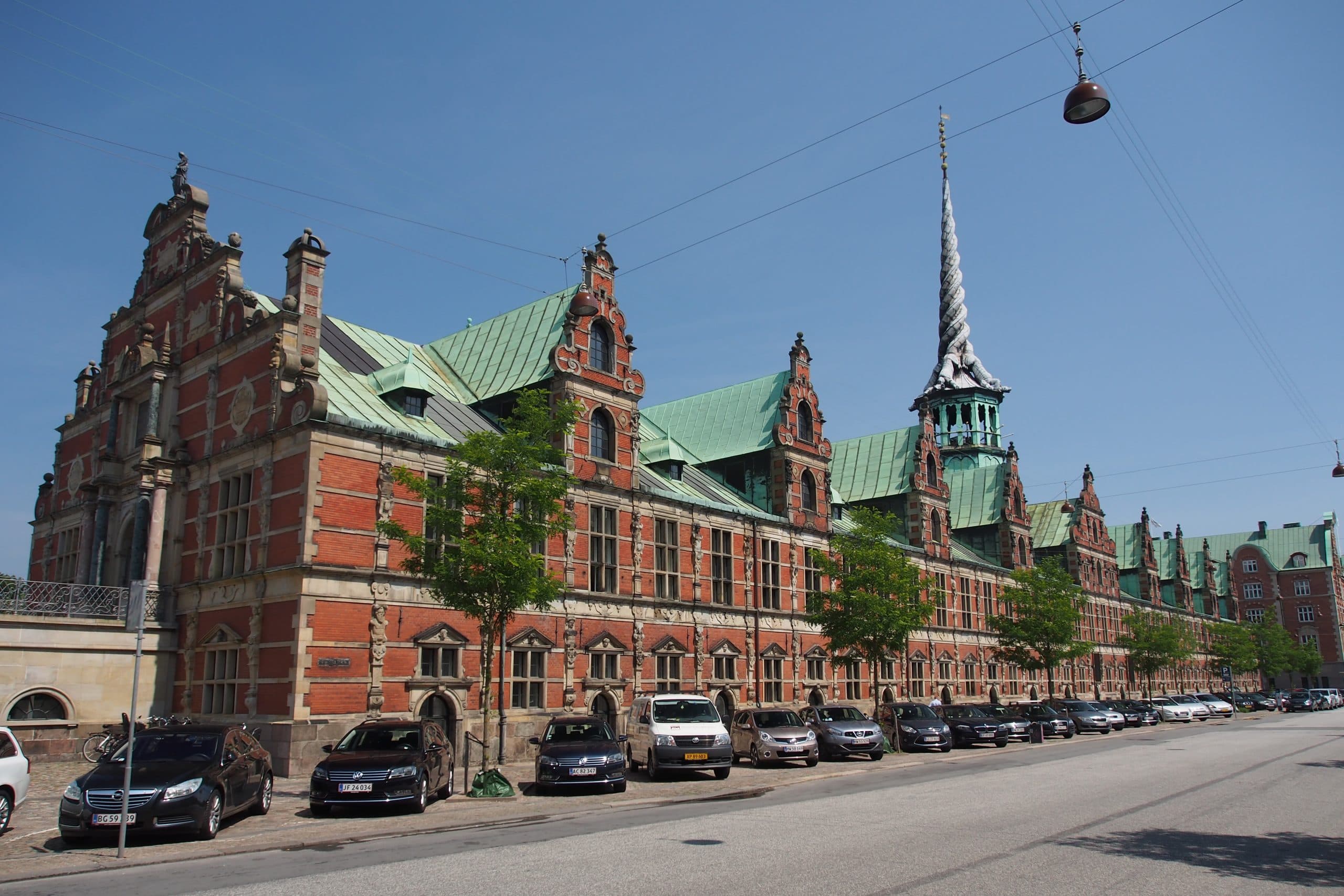 Old Stock Exchange building in Copenhagen with parked cars in front.