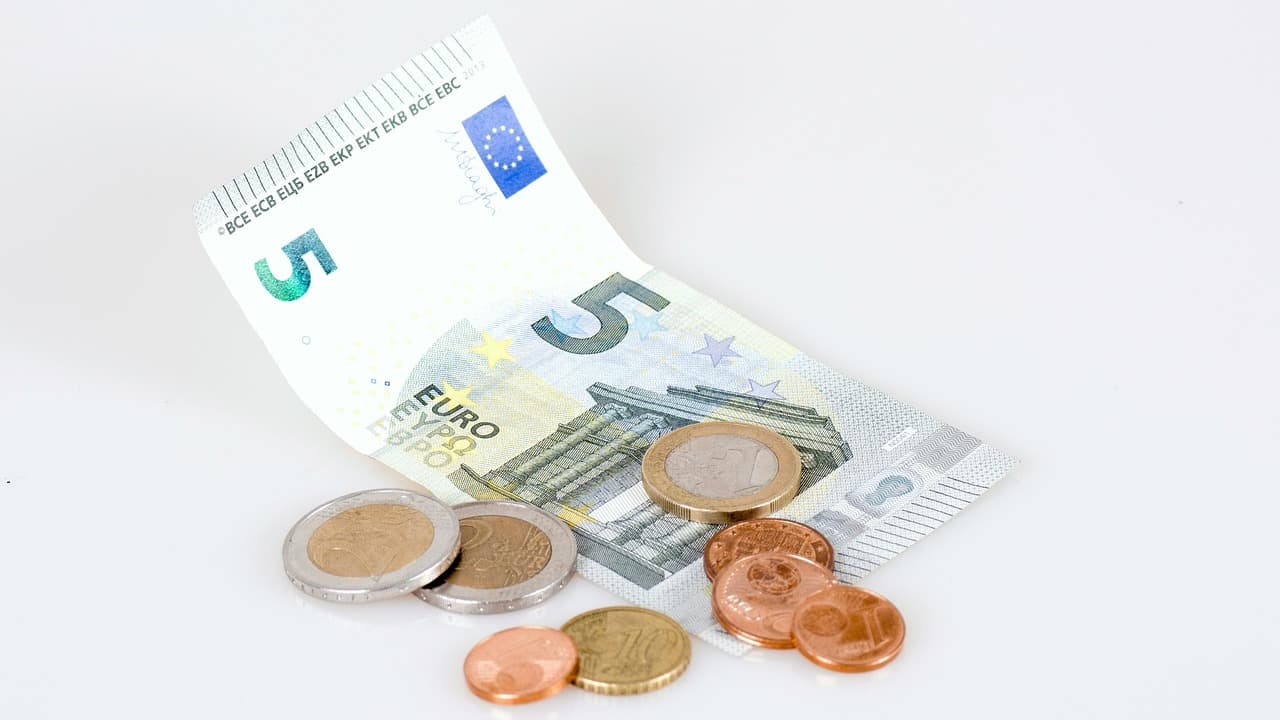Euro bills and coins on a white surface.