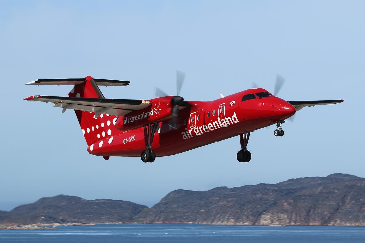 Ett flygplan från Air Greenland flyger över en kustlinje.