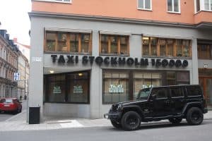 Exteriör av Taxi Stockholms kontor med ett svart fordon parkerat utanför.