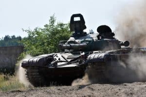 A military tank moving through a dusty terrain.