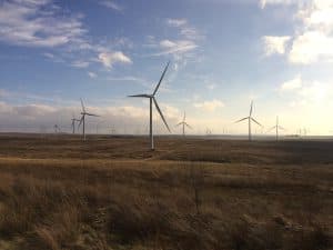 Vindkraftverk i ett vidsträckt öppet landskap under en molnig himmel.