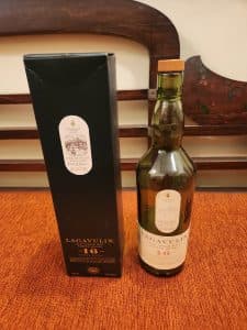 Flaska Lagavulin Single Malt Scotch Whisky och dess förpackning på ett bord.