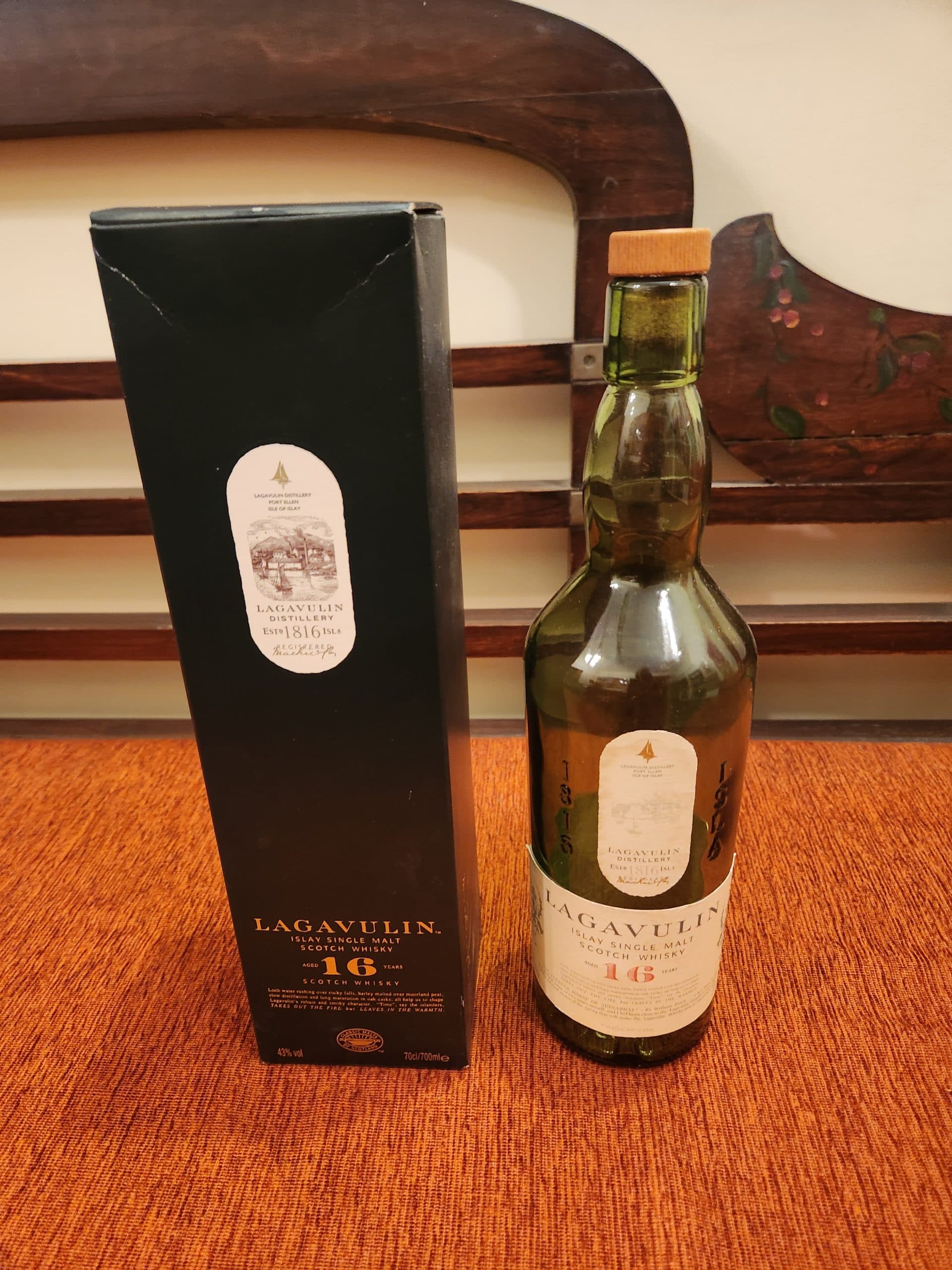 Flaska Lagavulin Single Malt Scotch Whisky och dess förpackning på ett bord.
