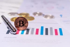 Bitcoin-mynt på ett papper med grafer och statistik.