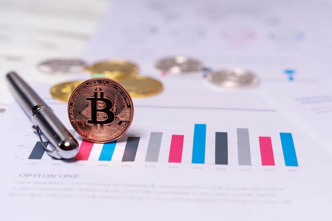 Bitcoin-mynt på ett papper med grafer och statistik.