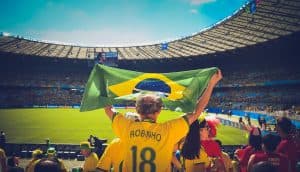 En fotbollssupporter som håller en brasiliansk flagga på en arena.