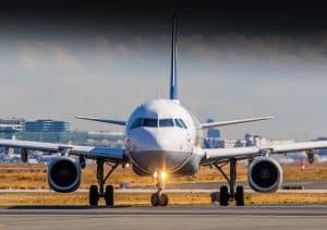 Ett flygplan på en landningsbana med stad i bakgrunden.