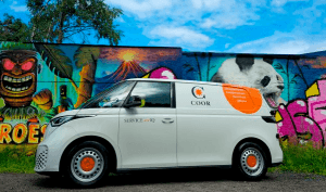 En vit skåpbil med Coor-logotypen framför en färgglad graffitivägg.