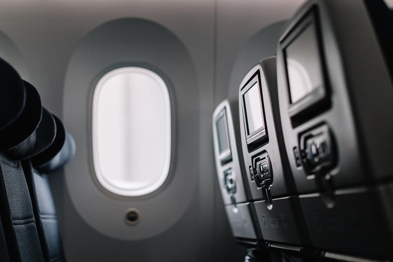 Interiör av ett flygplan med tomma säten och fönster.