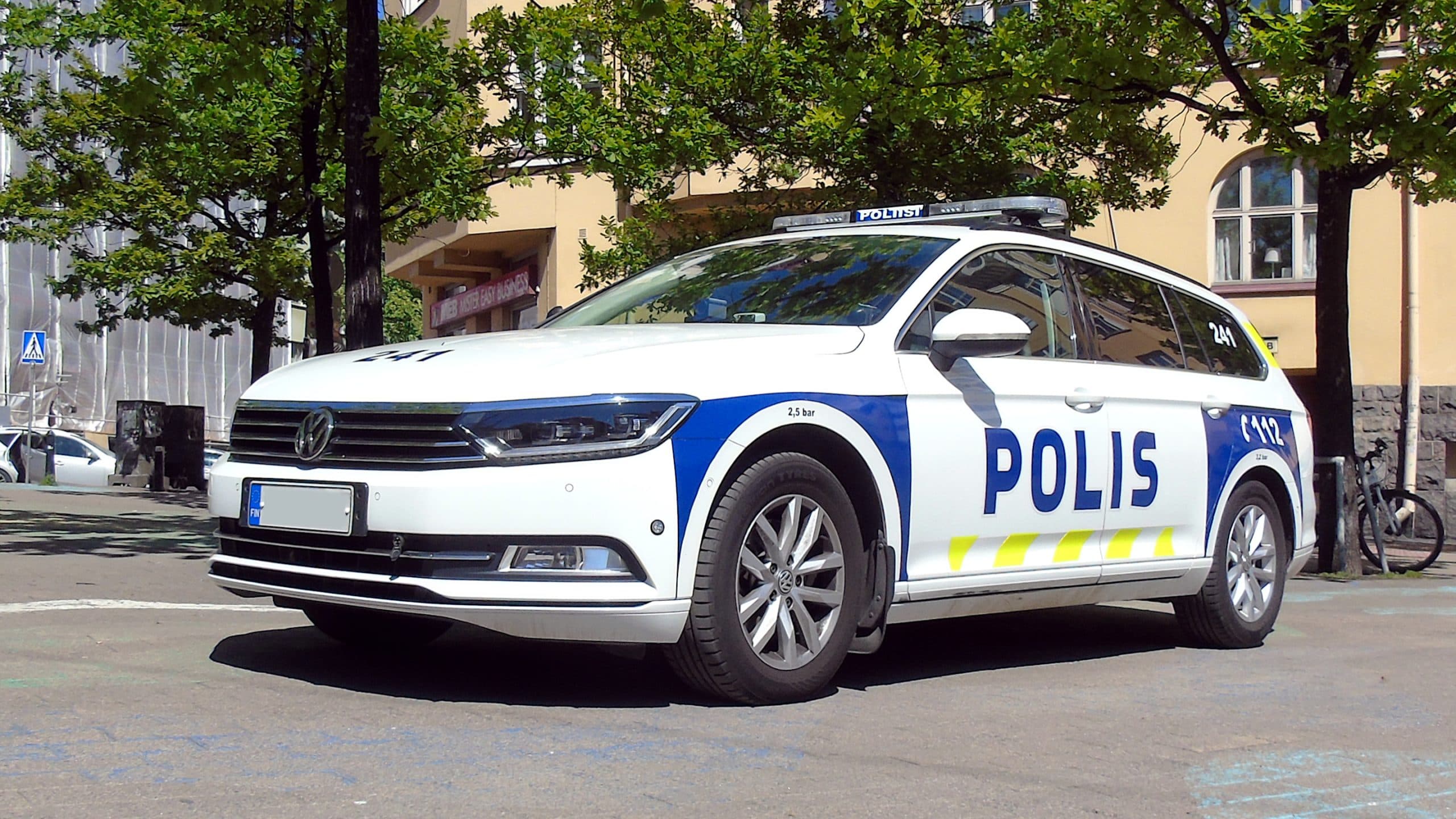 En vit Volkswagen Passat polisbil parkerad utomhus.