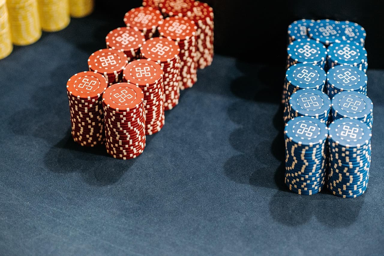 Poker chips in red, blue, and yellow stacked on a table.