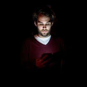 En man tittar på sin mobiltelefon i mörker.