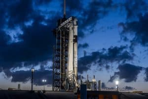 SpaceX rocket on launch pad at dusk with dramatic clouds.