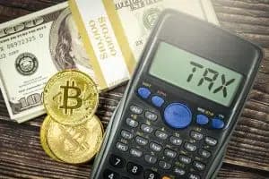Bitcoinmynt och en miniräknare med texten 'TAX' bredvid amerikanska dollarsedlar.