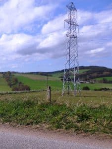 Elledningstorn på landsbygden under en blå himmel.