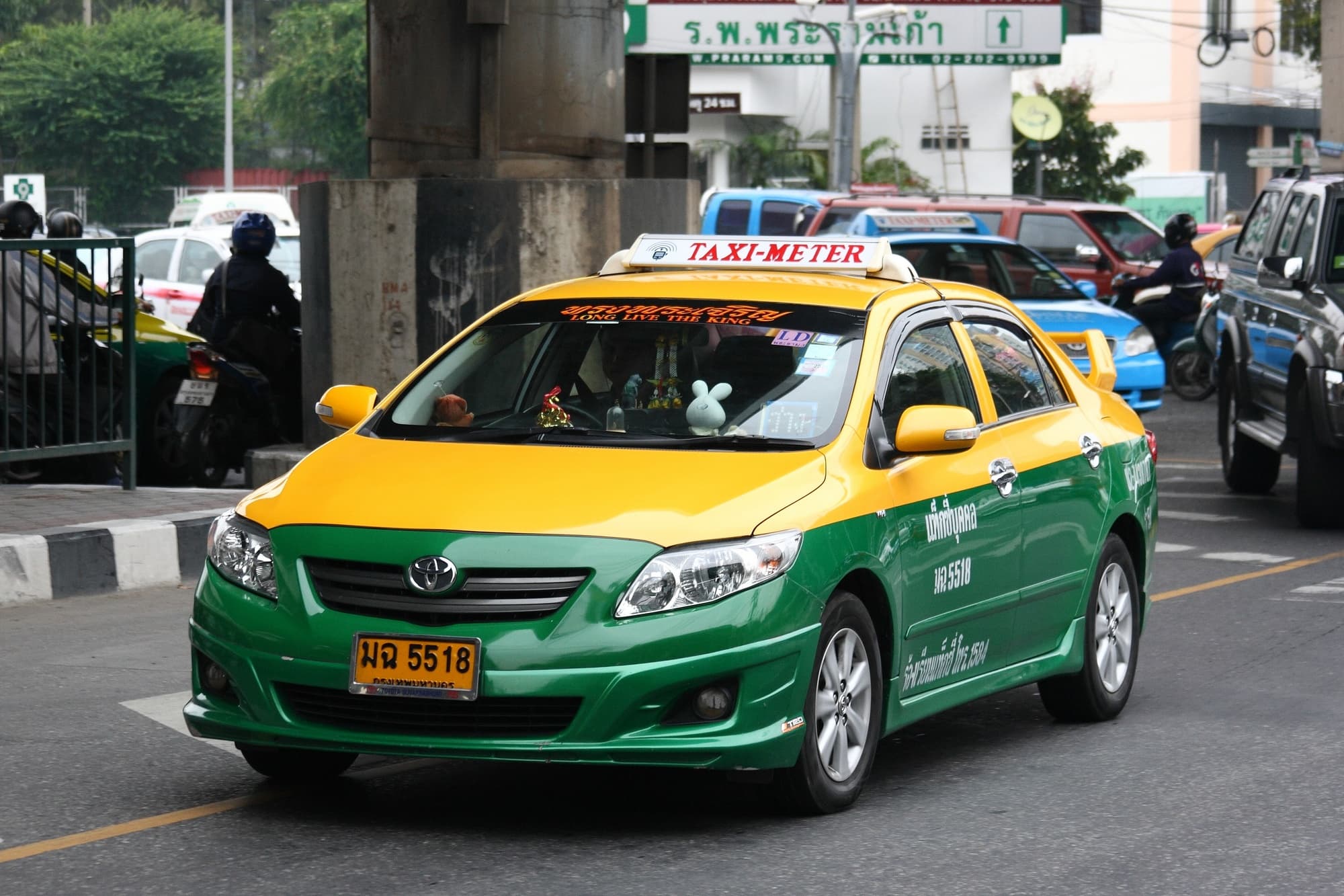 En gul och grön taxi med taxameter på en gata i Bangkok.