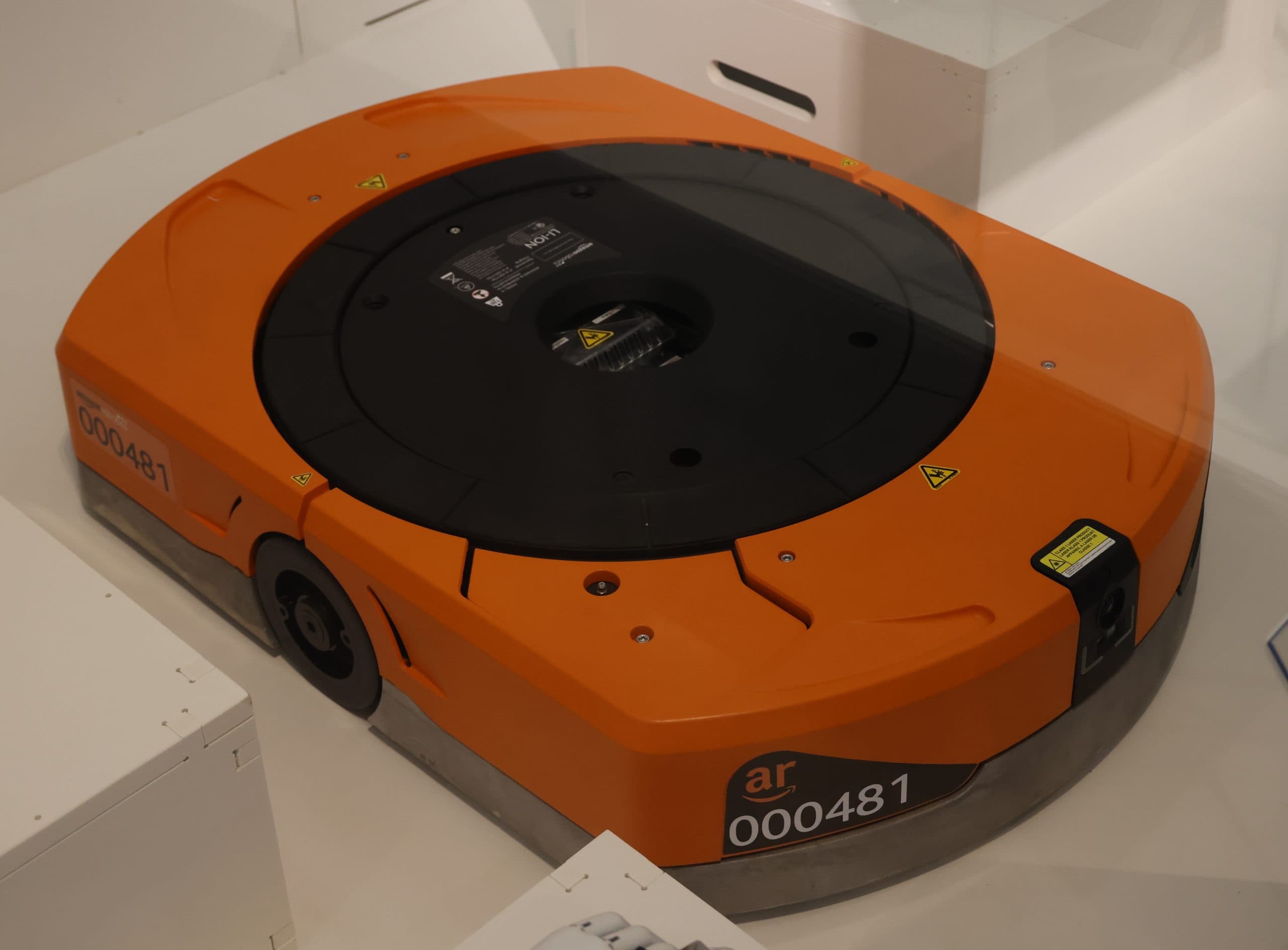 En orange robot på ett lagergolv.