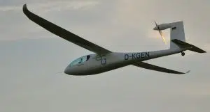 Ett elflygplan i luften mot en molnig himmel.