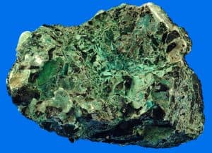Copper ore with green and black hues on a blue background.