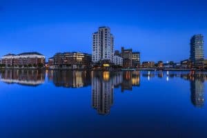 Vy över Dublins skyline vid skymning med reflektioner i vattnet.