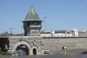 A prison with a guard tower and stone walls under a clear blue sky.