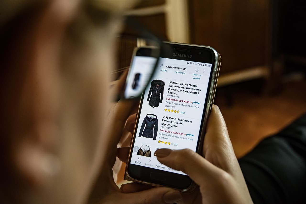 Person som använder en smartphone för att shoppa kläder online.